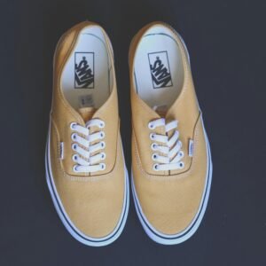 Pair of stylish yellow sneakers on a black background showcasing fashion and footwear design.